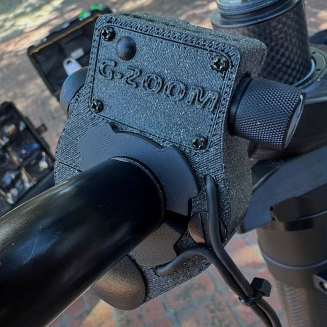 Close-up of a camera with a 'G-Zoom' attachment on a blurred background